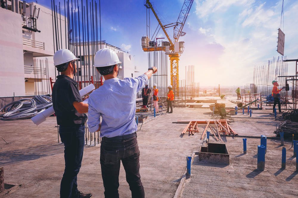 Modern building under construction with cranes and workers in action.